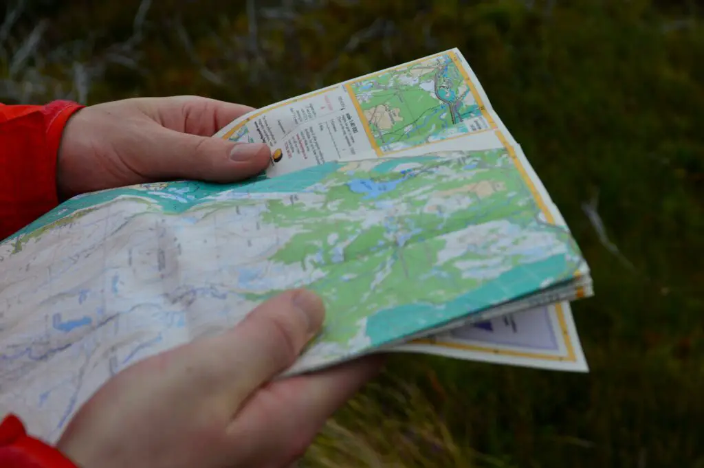 une personne consulte une carte topographique de randonnée pour trouver son chemin.