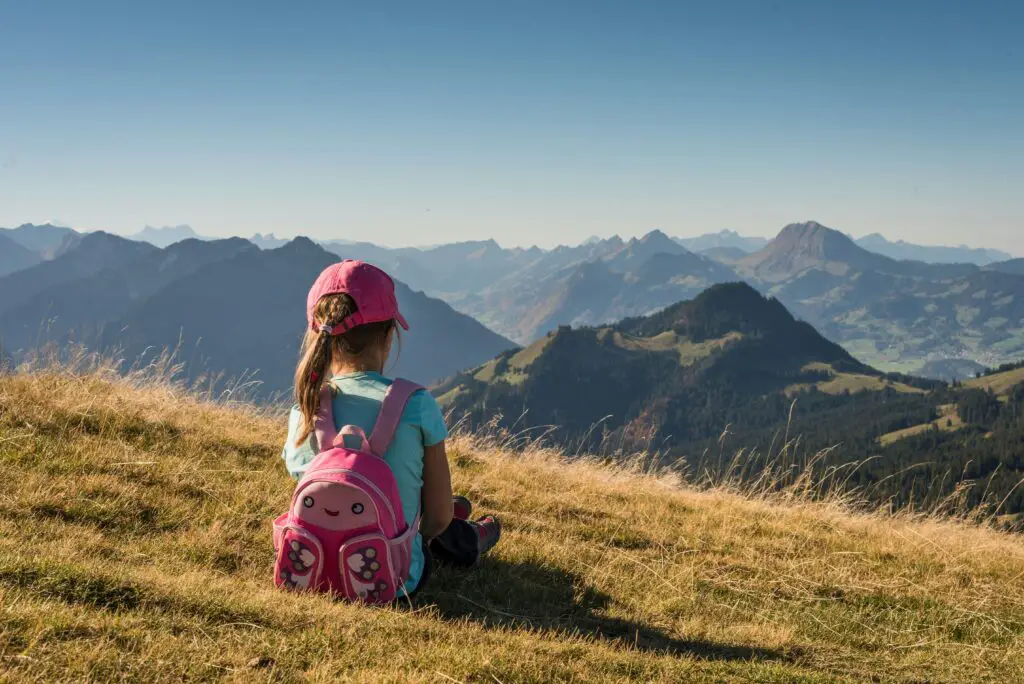 Petite fille assise et contemplant le paysage montagneux à l'horizon.